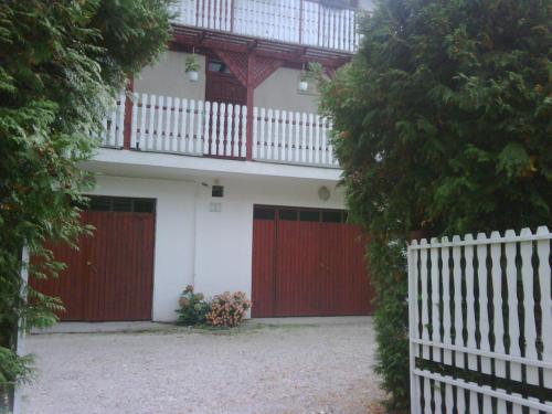 a house with red doors and a white fence at Relax Apartmanok in Zalakaros