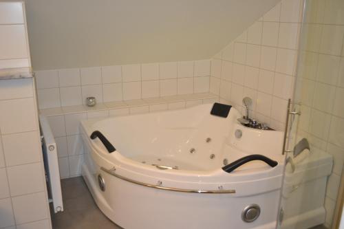 a white bath tub in a white tiled bathroom at Hotell Nostalgi in Motala
