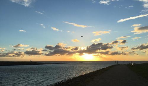 a sunset over a body of water with the sun setting at Heeren's Hotel Garni in Bensersiel