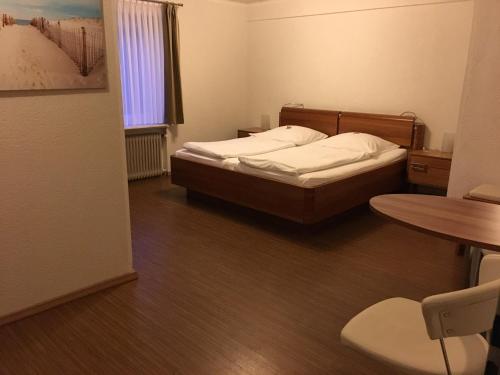 a small bedroom with a bed and a table at Heeren's Hotel Garni in Bensersiel