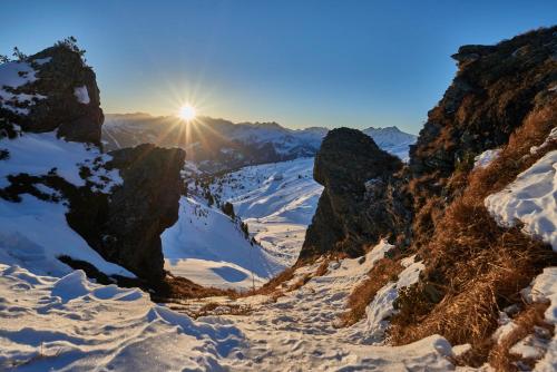 a snow covered mountain with the sun in the background at Berggasthof Platzlalm in Kaltenbach