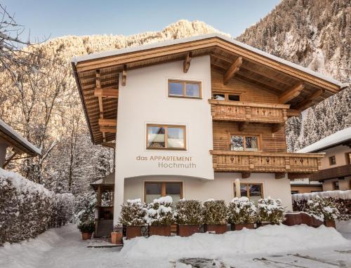 une maison dans la neige devant une montagne dans l'établissement Alpen Appartements Hochmuth, à Mayrhofen