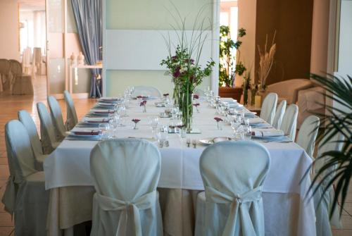 a long table with white tables and chairs and flowers at Hotel Sinuessa Terme in Mondragone