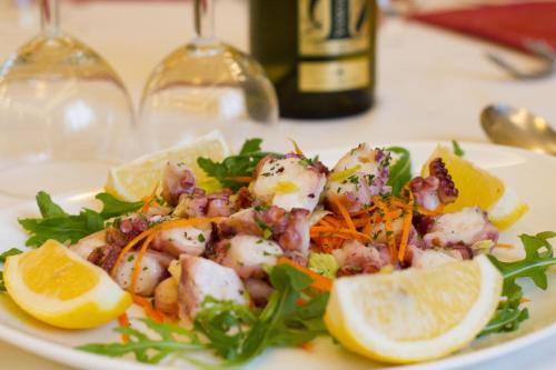 a plate of food with a salad and lemon slices at Pensione Al Pescatore in Termoli