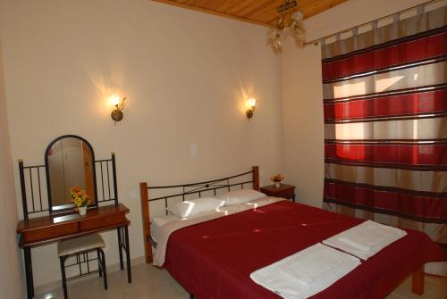 a bedroom with a red bed and a mirror at Garden View Apartments in Anaxos