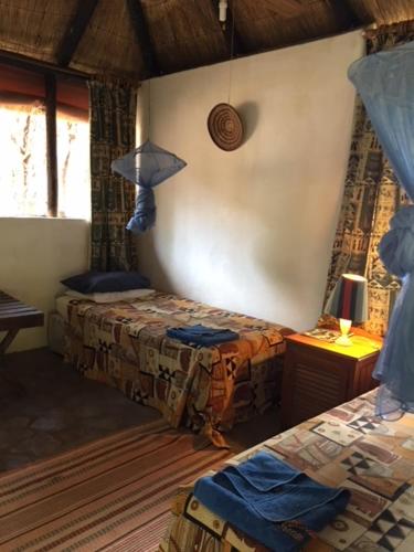 a bedroom with two beds and a lamp in a room at Sundowner Lodge in Hwange
