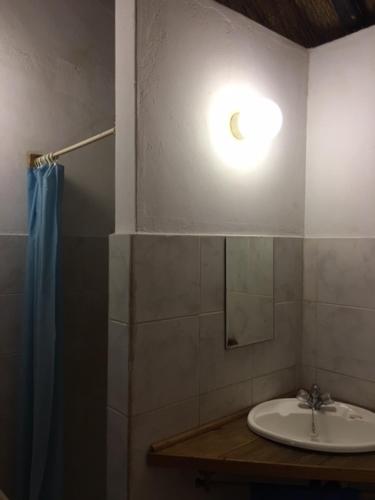 a bathroom with a sink and a light on the wall at Sundowner Lodge in Hwange