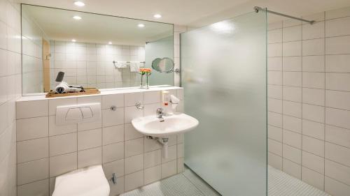 a bathroom with a toilet and a sink and a shower at Hotel Boldern in Männedorf