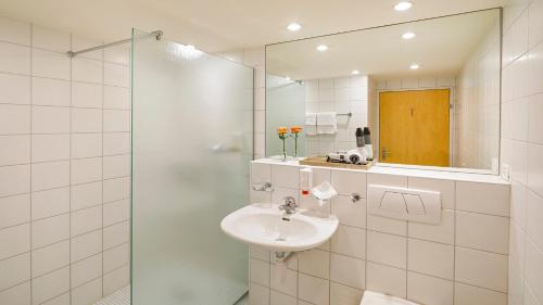 a bathroom with a sink and a glass shower at Hotel Boldern in Männedorf