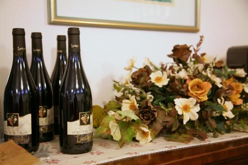 three bottles of wine sitting next to a flower arrangement at Cascina Lavaroni in Buttrio