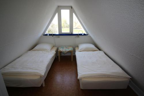 レンブルッフにあるHaus am Seeのベッド2台と窓が備わる屋根裏部屋です。