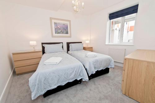 a white bedroom with two beds and a window at No 3 Central Chambers in Stratford-upon-Avon