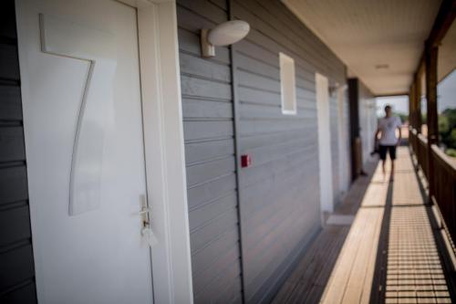 a woman walking down a hallway next to a door at La Petite Couronne, Ecolodge & Lofts in Saint-Cricq-Chalosse