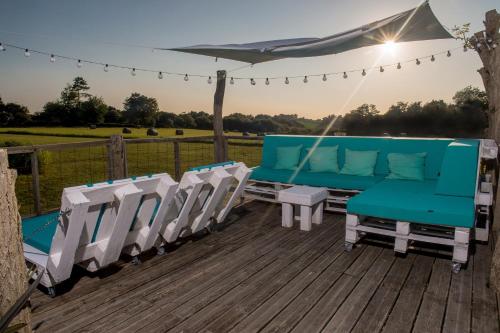 a deck with blue and white chairs and an umbrella at La Petite Couronne, Ecolodge & Lofts in Saint-Cricq-Chalosse
