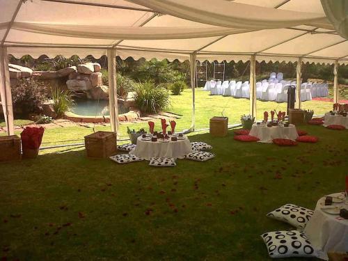 a white tent with tables and chairs in a field at African Silhouette Guesthouse in Benoni