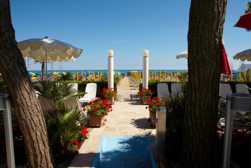 a walkway with flowers and umbrellas on the beach at Termini Beach Hotel & Suites in Lido di Jesolo