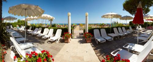 a group of lounge chairs and umbrellas on the beach at Termini Beach Hotel & Suites in Lido di Jesolo