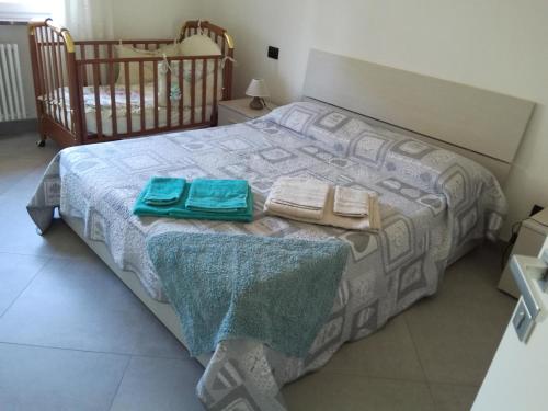 盧加尼亞諾的住宿－Affittacamere Di Paola，一间卧室配有一张带两条毛巾和一张婴儿床的床。