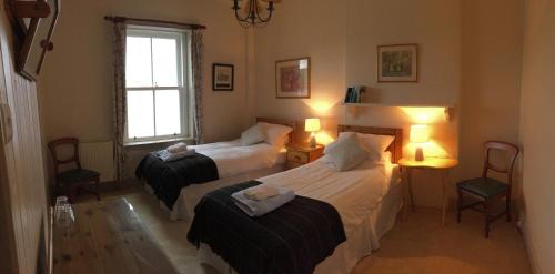 a bedroom with two beds and two chairs and a window at Uig Lodge in Uig