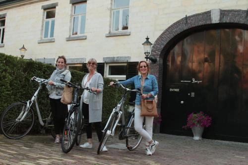 three women standing with their bikes in front of a building at Boutique Hotel Bonjour in Gronsveld