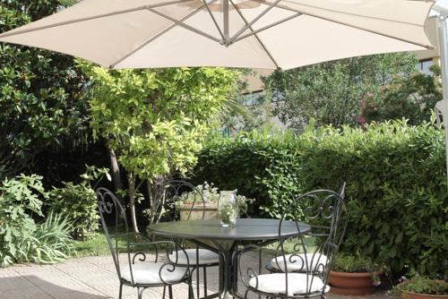 a table and chairs under a white umbrella at Hotel City in Piacenza