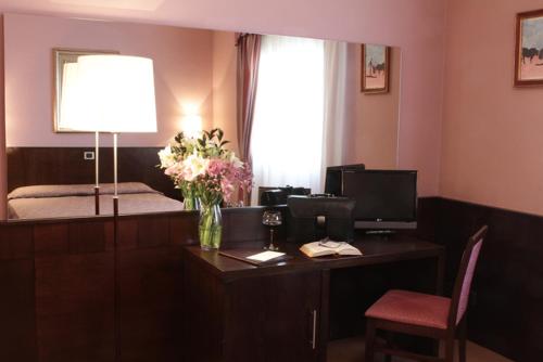 a room with a desk with a vase of flowers on it at Hotel City in Piacenza