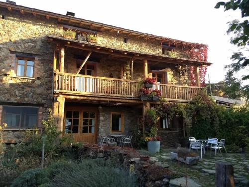 a stone house with a balcony and tables and chairs at Hostal D'Éller in Éller