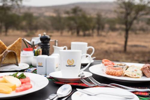 a table with plates of food and a cup of coffee at Ole Serai Luxury Camp in Serengeti National Park