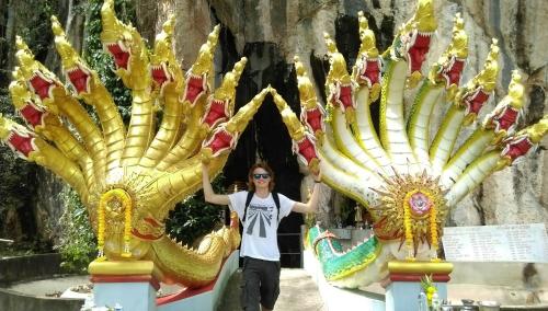 a woman standing in front of two golden statues at Salsa Hostel in Chumphon
