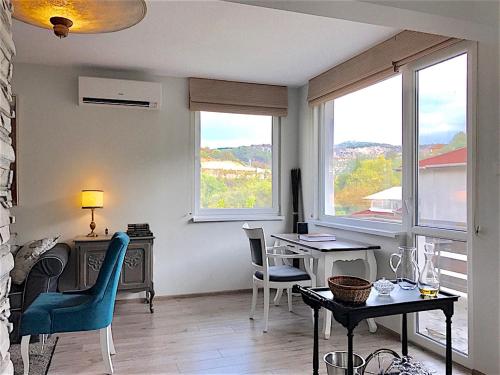 a living room with a table and chairs and windows at Penthouse Tsarevets in Veliko Tŭrnovo