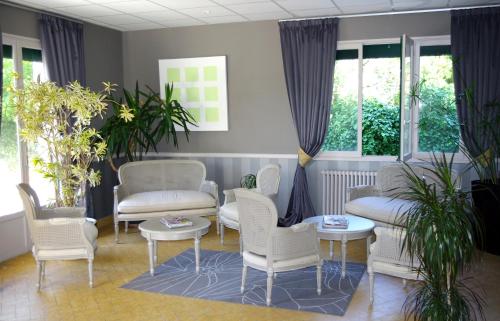 a waiting room with white chairs and tables and windows at Hotel des Pins in Soulac-sur-Mer