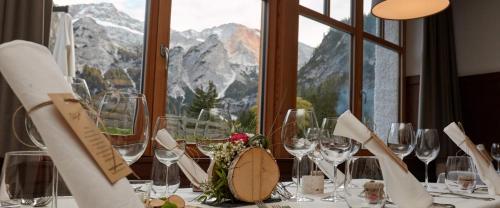 a table with wine glasses and a view of mountains at Alpin Natur Hotel Brückele in Braies