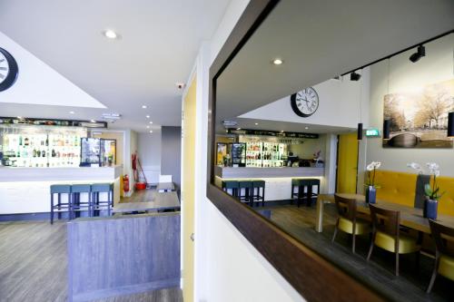 a bar in a restaurant with a clock on the wall at City Hotel Amsterdam in Amsterdam