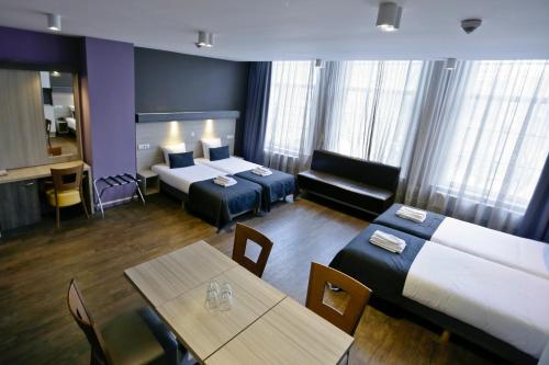 a hotel room with two beds and a table at City Hotel Amsterdam in Amsterdam