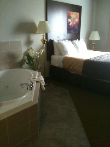 a bathroom with a bed and a bath tub next to a sink at Super 8 by Wyndham Innisfail in Innisfail