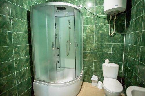 a green tiled bathroom with a shower and a toilet at Premium Hotel in Izmail