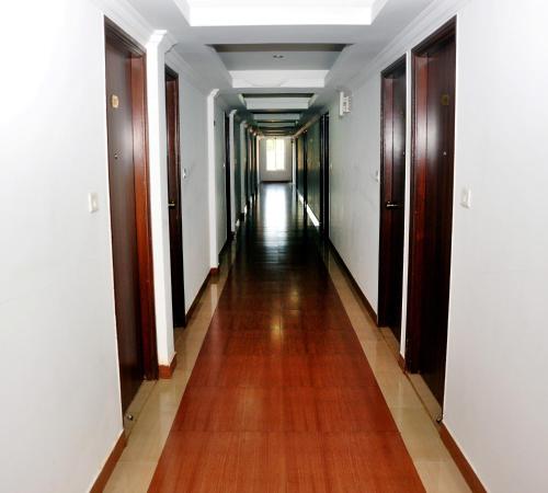 a long hallway with wooden floors and white walls at Emporium Hotel in Mangalore