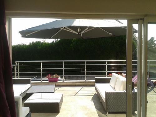 a patio with an umbrella and a couch and tables at Chambres d'Hôtes Poirier Bazin in Montry