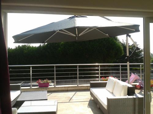 a patio with an umbrella and a couch and a table at Chambres d'Hôtes Poirier Bazin in Montry