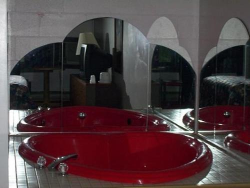 uma banheira vermelha numa casa de banho com dois espelhos em Passport Inn and Suites - Middletown em Middletown