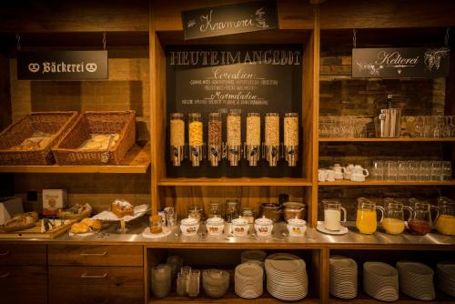 a kitchen with a shelf with plates and drinks at Alpenstadthotels in Bad Reichenhall
