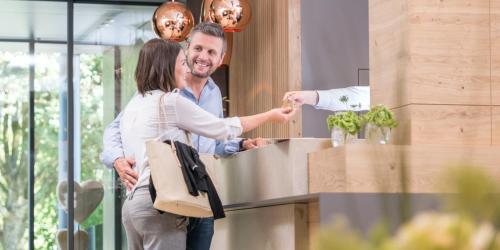 a man and a woman standing at a counter at Hotel Riedenburg in Bad Füssing
