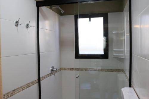 a bathroom with a shower and a tub with a window at Posada de la Viuda in Punta Del Diablo