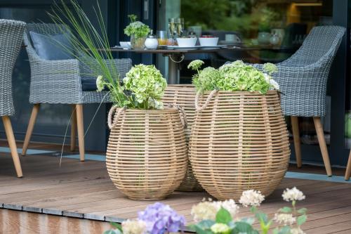 three wicker planters with plants in them on a patio at Hotel Riedenburg in Bad Füssing