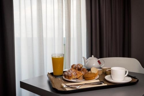 a tray with breakfast foods and a glass of orange juice at JR Hotels Gigli Firenze in Calenzano