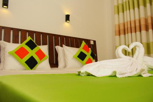 two white swans sitting on a green bed at Cozy Sea view Inn in Hikkaduwa