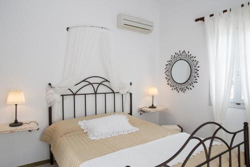 a white bedroom with a bed and a mirror at Irini pension in Platis Yialos Sifnos
