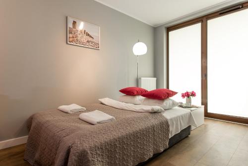 una camera da letto con un grande letto con cuscini rossi di P&O Apartments Ordona 2 a Varsavia