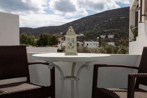 a table on a balcony with two chairs and a lantern at Irini pension in Platis Yialos Sifnos