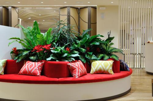 a red couch with a bunch of plants on it at JR Hotels Gigli Firenze in Calenzano
